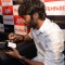 Dhanush signs a mug at the Filmfare Readers Meet at the Reliance Digital Store